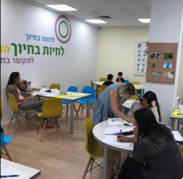 משתתפים לומדים סביב שולחנות בחדר ההדרכה של מרכז חיוך