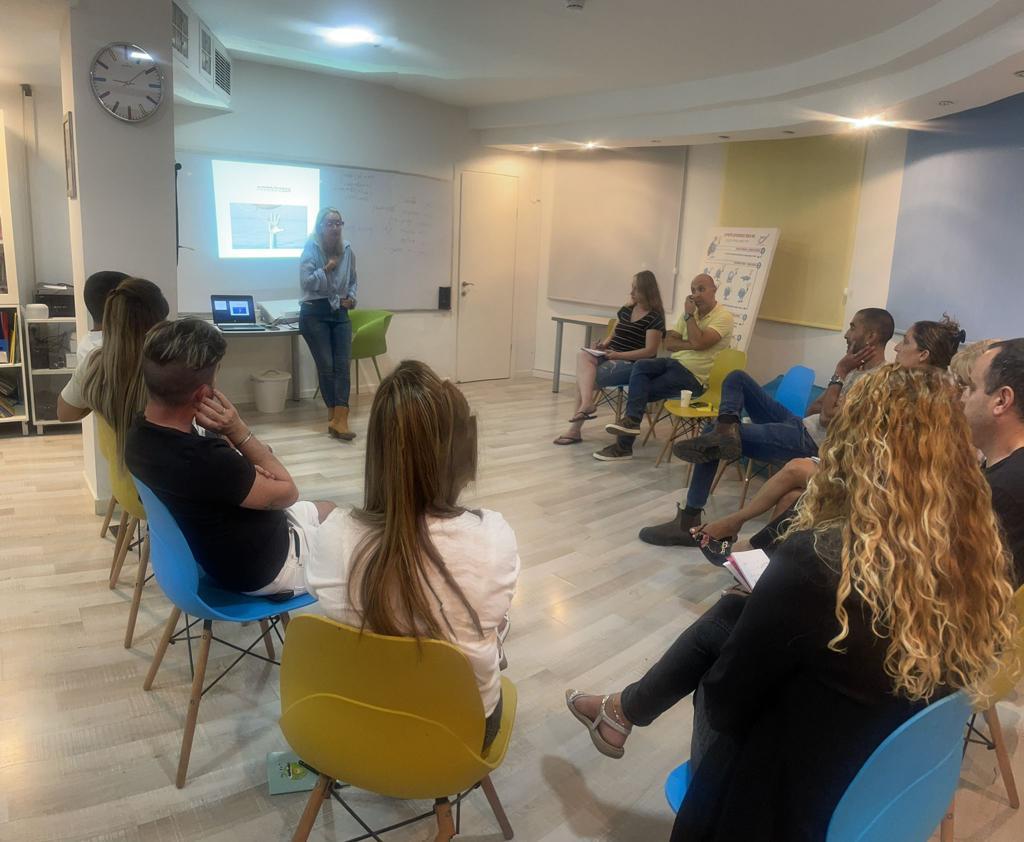 מרצה מעבירה הדרכת הורים מול מצגת וקהל משתתפים
