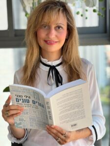 אירנה צינמן מצוות מרכז חיוך מחזיקה את הספר הורים טובים