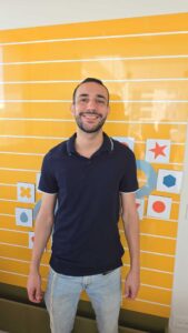 עדיאל בנטולילה מצוות מרכז חיוך על רקע קיר צורות צהוב